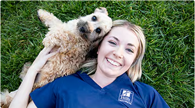 Femeie întinsă pe iarbă, cu un câine alături