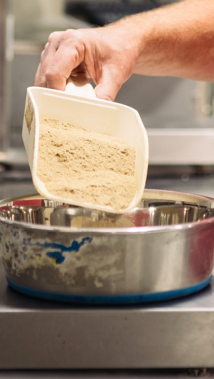 Un angajat Hill's măsoară ingredientele pe un cântar