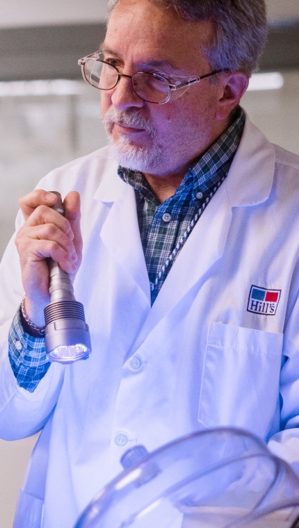 Un om de știință de la Hill's ține o lanternă pentru a demonstra munca de laborator copiilor